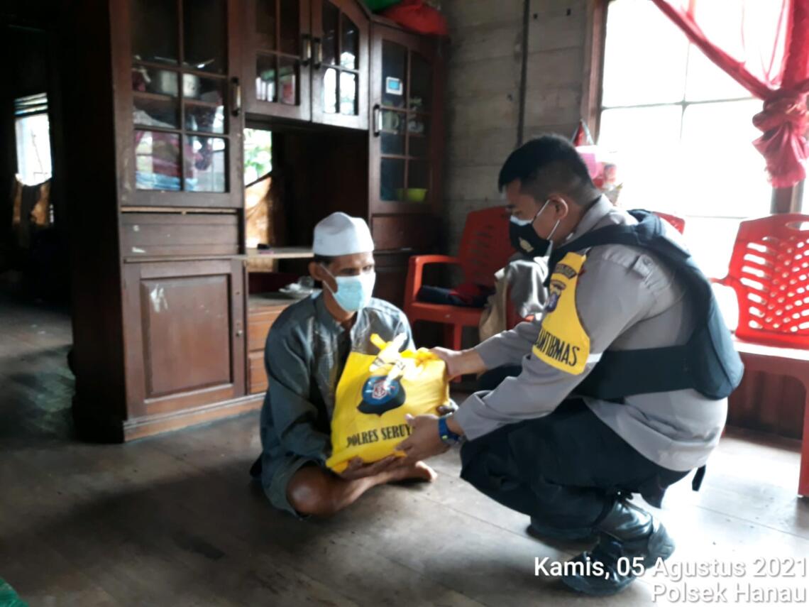 Polisi Sektor (Polsek) Hanau  melakukan kegiatan sosial, dengan membagikan bantuan sosial (Bansos) yang berupa beras dan bahan pokok lainnya kepada masyarakat yang terdampak wabah Covid-19, Kamis (5/8/2021). Foto : Tbn