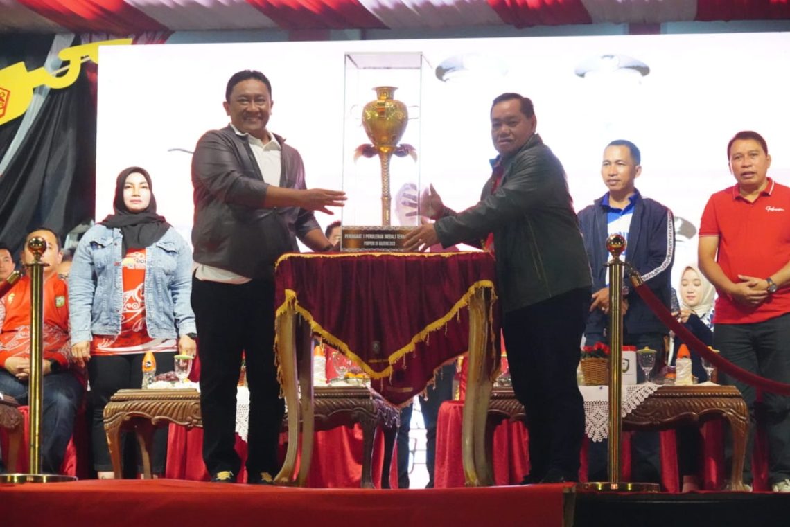 Wakil Gubernur Kalteng H. Edy Pratowo saat menyerahkan piala juara umum kepada Bupati Kotawaringin Timur Halikinnor