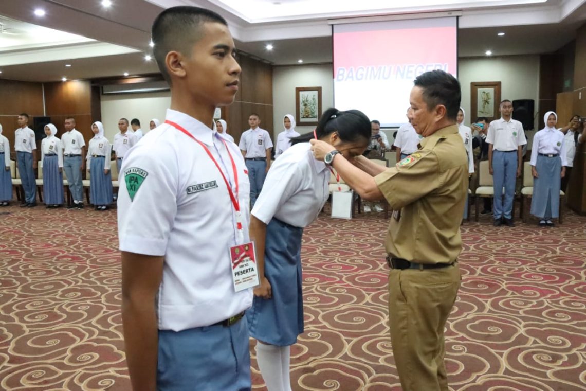 Sahli Gubernur bidang KSDM saat memasang tanda peserta secara simbolis kepada peserta Diklat Paskibraka Tahun 2023