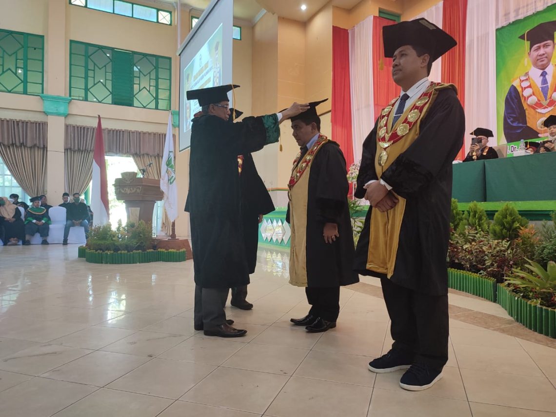 Rektor IAIN Palangka Raya H. Khairil Anwar bersama Ketua Senat IAIN Palangka Raya Mazrur saat memasangkan Baju Toga dan mengalungkan Gordon kepada Guru Besar IAIN Palangka Raya yang dikukuhkan. Foto : red