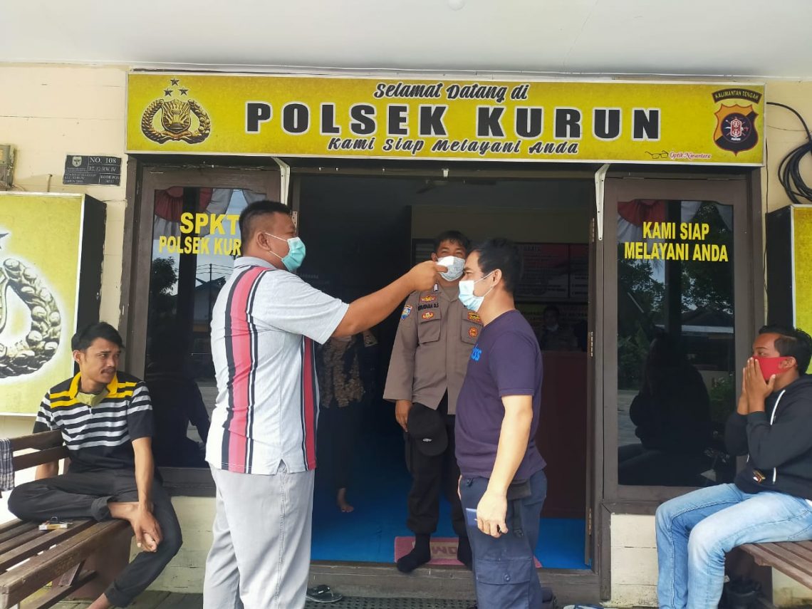 Anggota Polsek Kurun saat mengecek suhu tubuh warga yang akan berurusan di Mapolsek. FOTO : tbn.
