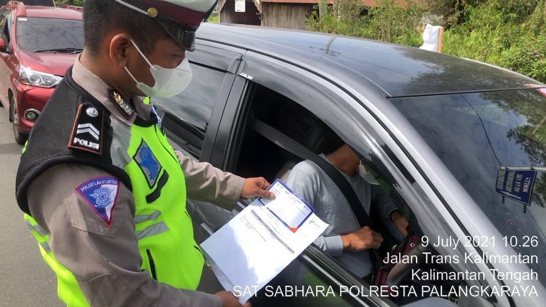 Polisi memeriksa surat keterangan bebas covid-19 berupa hasil tes negatif Swab PCR di pos penyekatan Jl Mahir Mahar Palangka Raya, Jumat (9/7/2021. Foto : TN