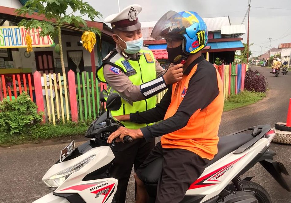 Petugas Sat Lantas membantu mengklikkan hel pengendara sepeda motor, Selasa (12/1/2021). Foto : Tbn