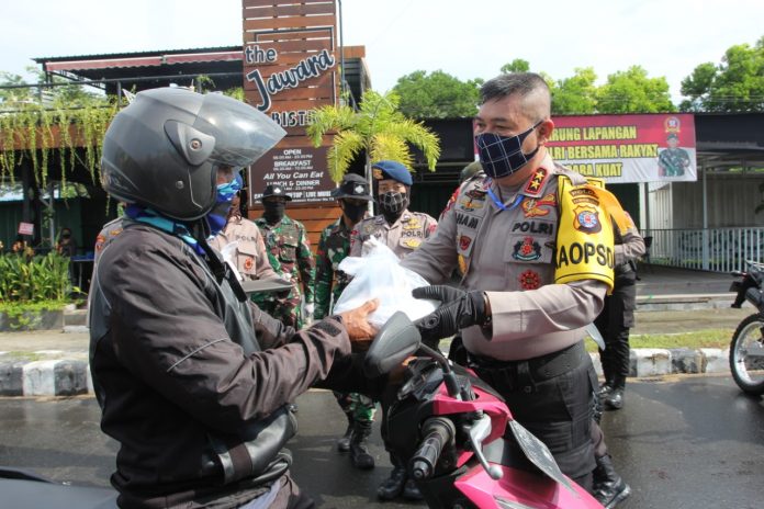 Kapolda Kalteng membagikan nasi kotak kepada warga yang melintas di Jalan Yos Sudarso Palangka Raya, Jumat (17/4/2020). Foto : fer