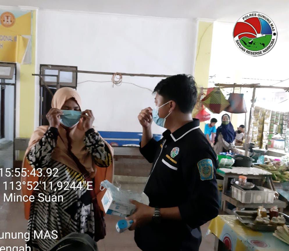 Anggota Satresnarkoba Polres Gumas sedang membagikan masker kepada pengunjung pasar Kuala Kurun. FOTO : tbn.