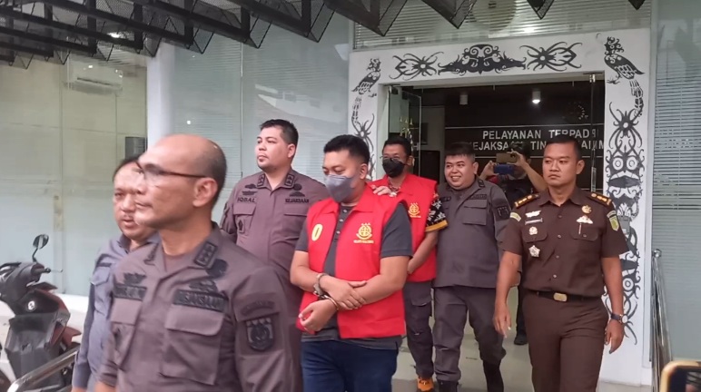 Tersangka RRH dan TF mengenakan rompi merah dengan tangan terborgol digiring ke mobil tahanan menuju Rutan Palangka Raya, Kamis (28/12/2023) sore. Foto: fernando rajagukguk