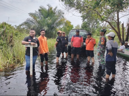 Bhabinkamtibmas Bripka Mokh Abdullah Edris, bersama tim gabungan melakukan patroli dan pengecekan wilayah terdampak banjir di Kelurahan Petuk Katimpun, Jumat (21/3/2025). Foto: Siehms.