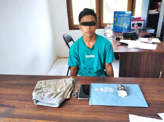 Pelaku HI (20) bersama paket sabu dan barang bukti lainnya saat diperiksa. FOTO : tbn.