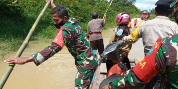 Babinsa 01/Bulik Sigap Bantu Seberangkan Warga dan Motor yang Terjebak Banjir