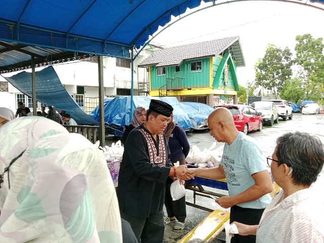 Kajari Palangka Raya Andi Murji Machfud (berkopiah) memberikan sekantong daging hewan kurban kepada salah seorang warga di halaman kejari setempat, Minggu (2/7/2023) siang. (Ist)