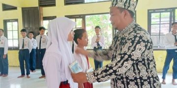 Kepala SMPN 1 Katingan Kuala, M.Yusri membuka kegiatan MPLS Menyenangkan ditandai dengan pemasangan papan nama peserta didik baru. (Foto: ist)