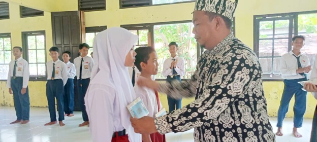 Kepala SMPN 1 Katingan Kuala, M.Yusri membuka kegiatan MPLS Menyenangkan ditandai dengan pemasangan papan nama peserta didik baru. (Foto: ist)